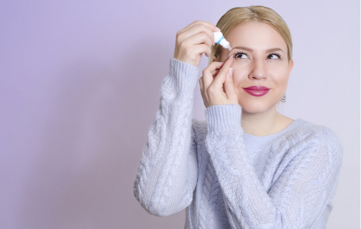 woman using eye drops to treat pink eye