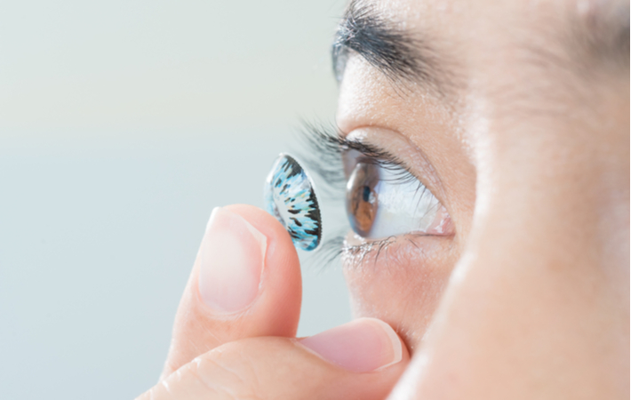 close-up of someone putting in a blue coloured contact lens