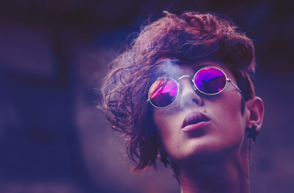 woman with short curly hair and round polarized glasses with the city skyline reflecting in her glasses