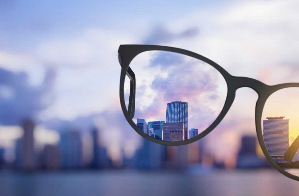 Blurred city scape at sunset with glasses in the forefront and the scene clear through the glasses' lens