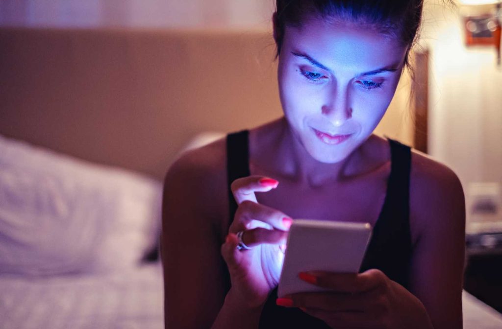 a smartphone bathing a woman sitting on a bed in HEV light