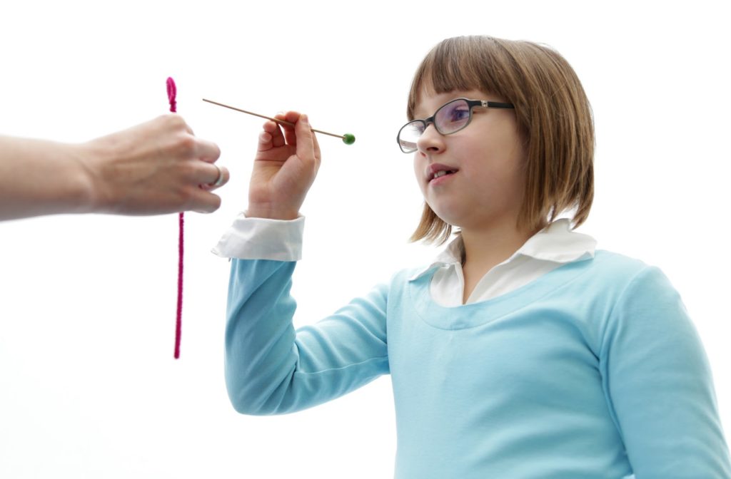 A little girl performing eye vision therapy to prevent lazy eye