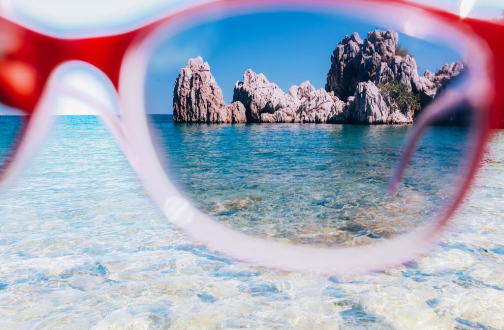 A view through the lens of polarized sunglasses looking towards a rock formation surrounded by beautiful blue water