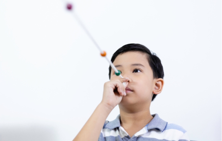 A young boy performing eye exercises looking down a string with blocks spaced out along the string