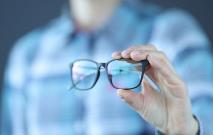 A person holding out a pair of black glasses in front of them