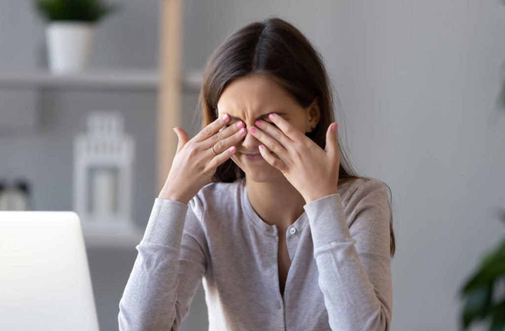 A woman holding her hands up to her eyes in response to the uncomfortable symptoms of dry eye disease