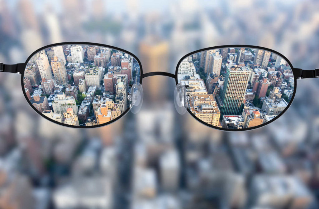 The view of a blurry city with glasses to correct the refractive error and result in clear vision.