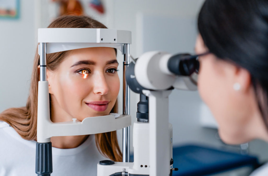 A woman looking into a medical device that her optometrist is using to detect eye problems.