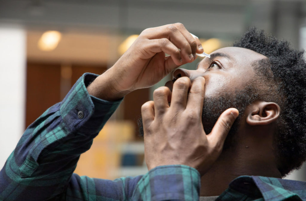 Young man using artificial tears to prevent dry eyes.