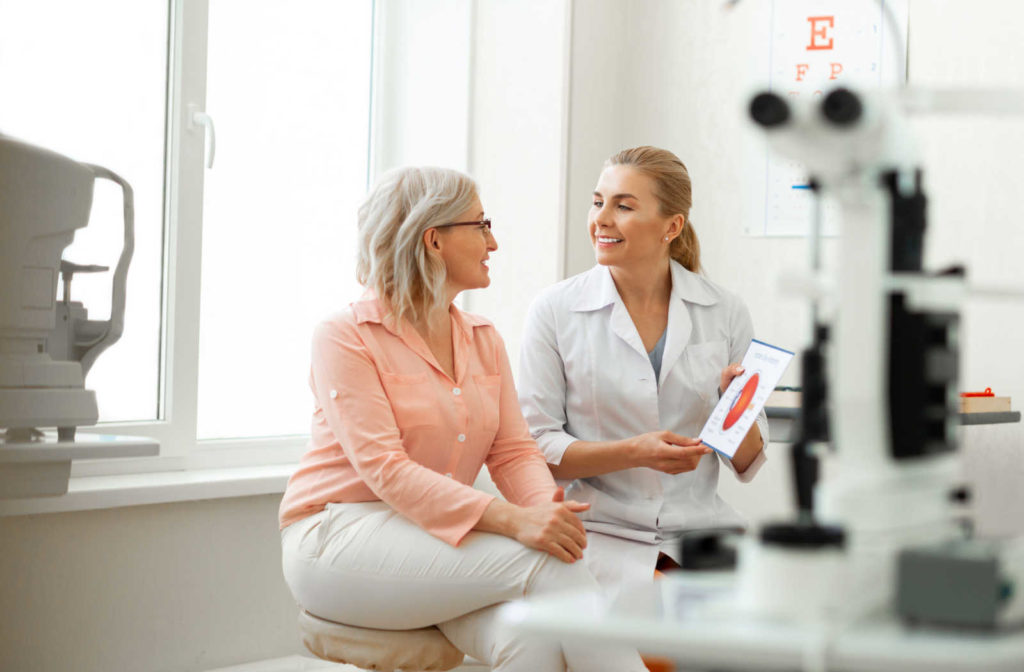 A woman sitting in an optometrist's office and smiling at her eye doctor.