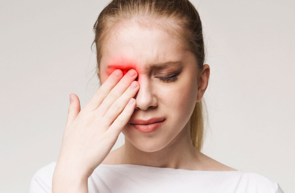 A young woman rubbing her right eye with her right hand, with a concerned look on her face